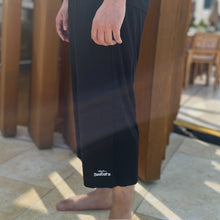 Load image into Gallery viewer, Black long swim shorts, with white logo and waistband
